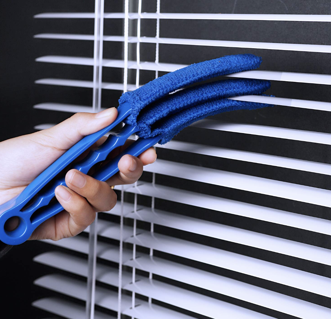 a person using the cleaner on a set of blinds