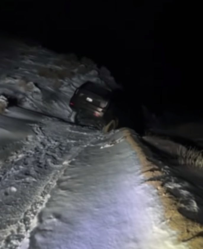 An SUV stuck in a snow covered ditch