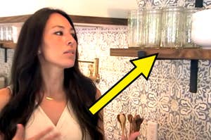 Joanna Gaines looking at an open shelf with mason jars on it in a kitchen