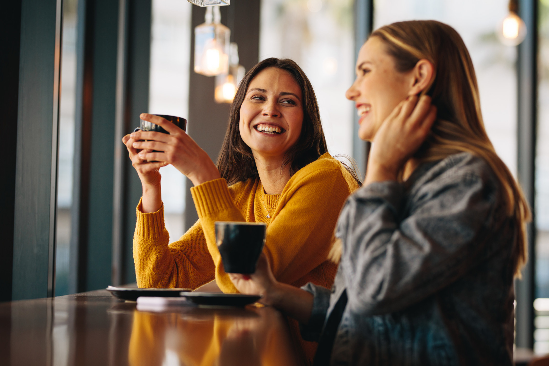 Two women drinking coffee and laughing