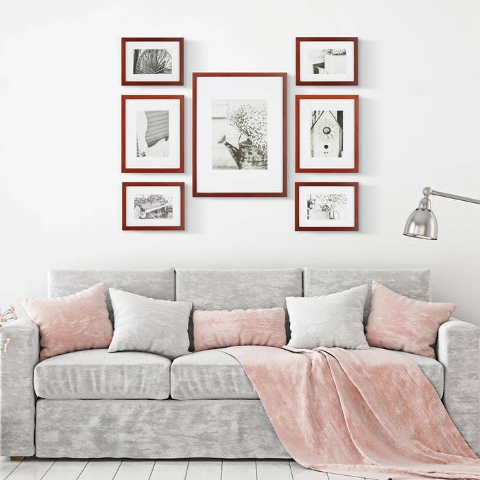 The set of seven frames of various sizes hanging above a couch