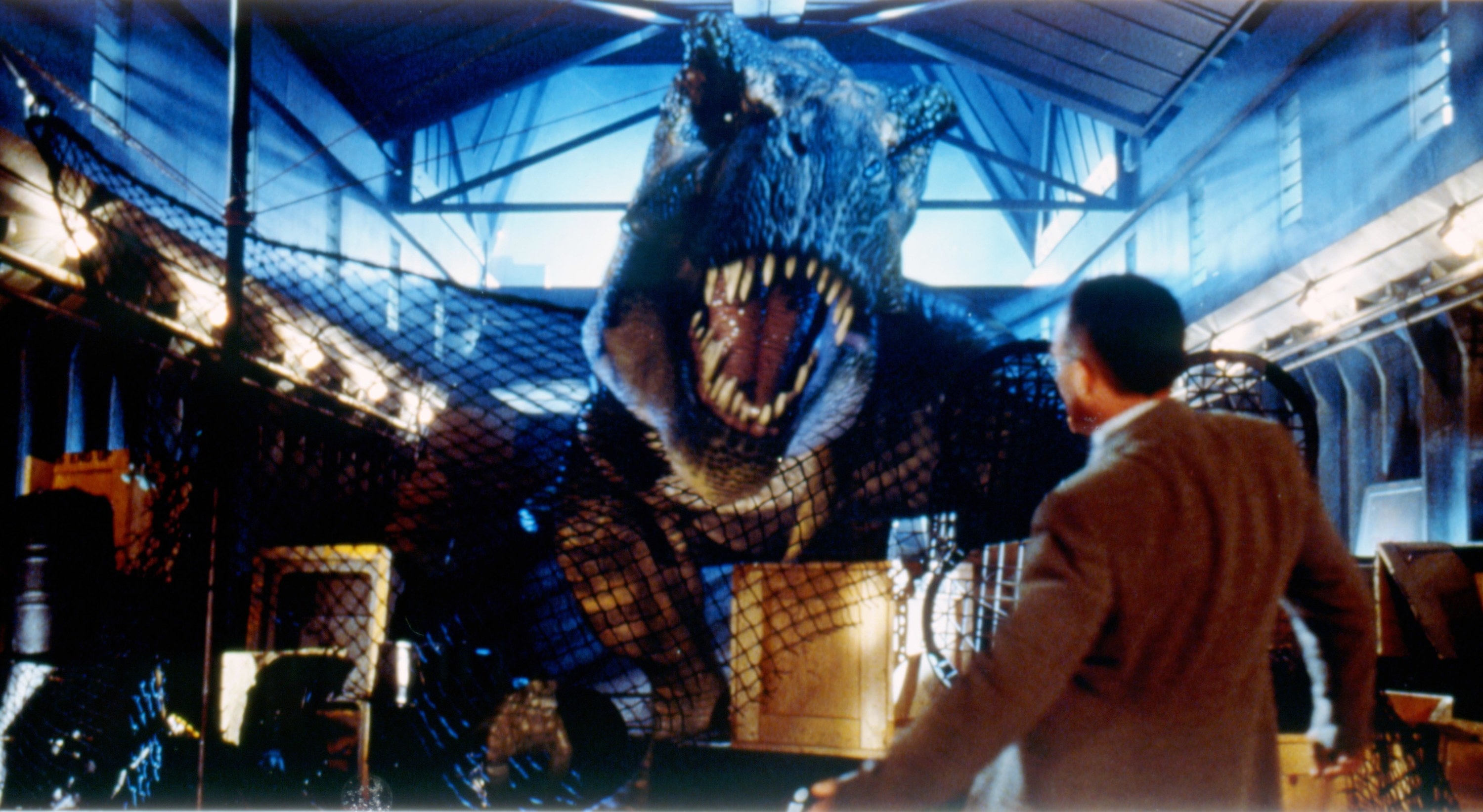 A tyrannosaurus rex roars at someone in a warehouse