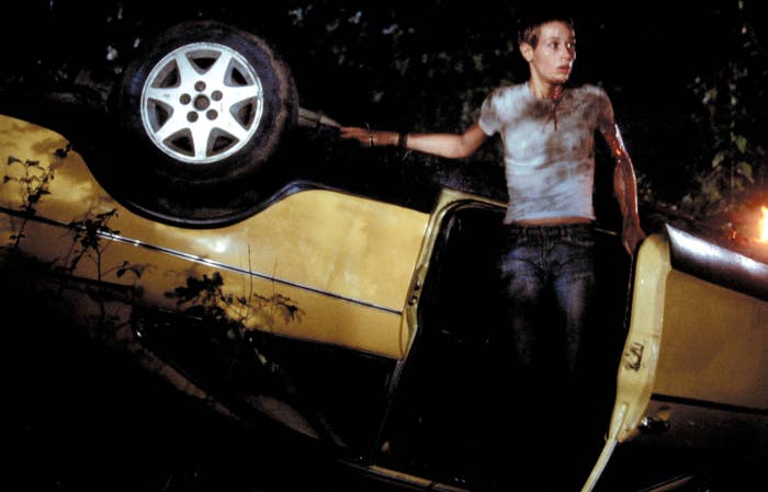 A wounded young woman emerges from a capsized car