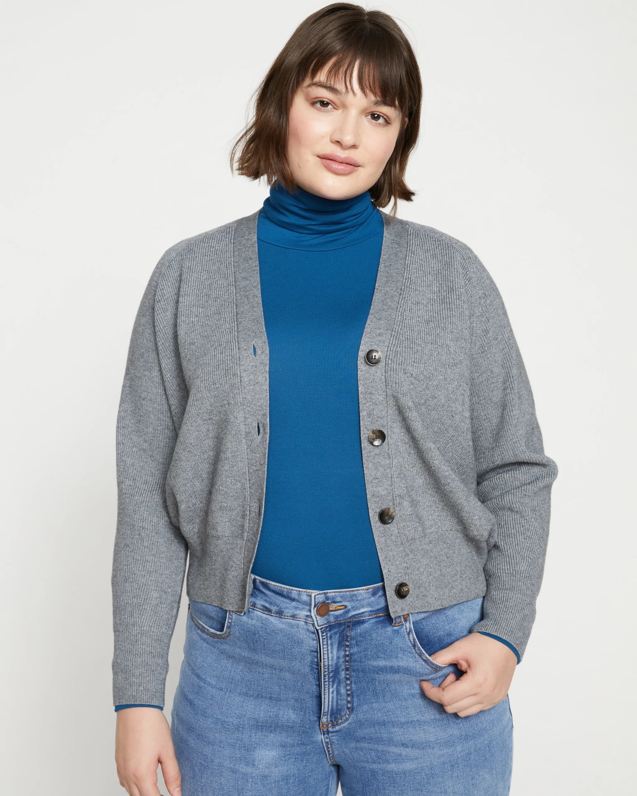 Model wearing blue turtleneck, grey cardigan and jeans