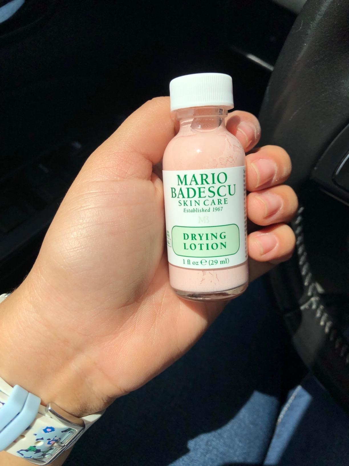 reviewer holding the bottle of the drying lotion