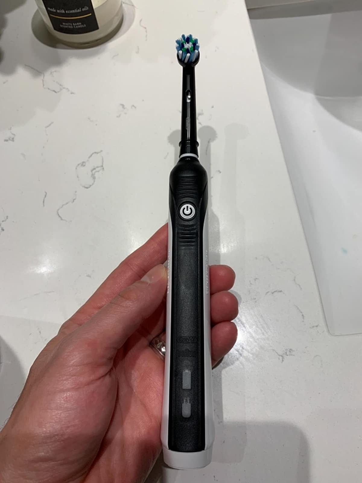 A reviewer holding the black and white electric toothbrush