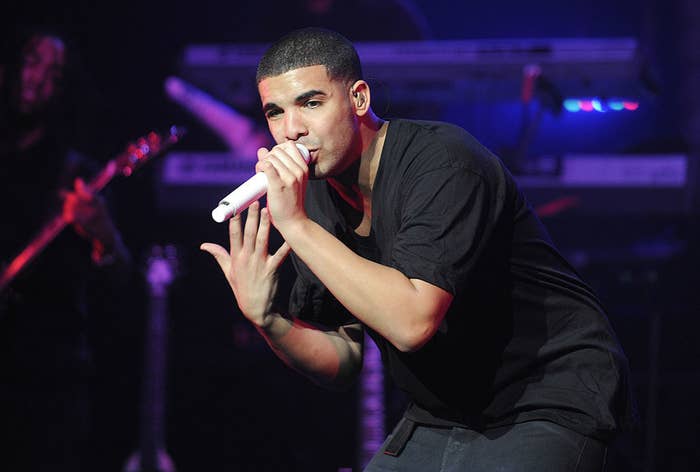 A youthful drake raps onstage in a black t shirt