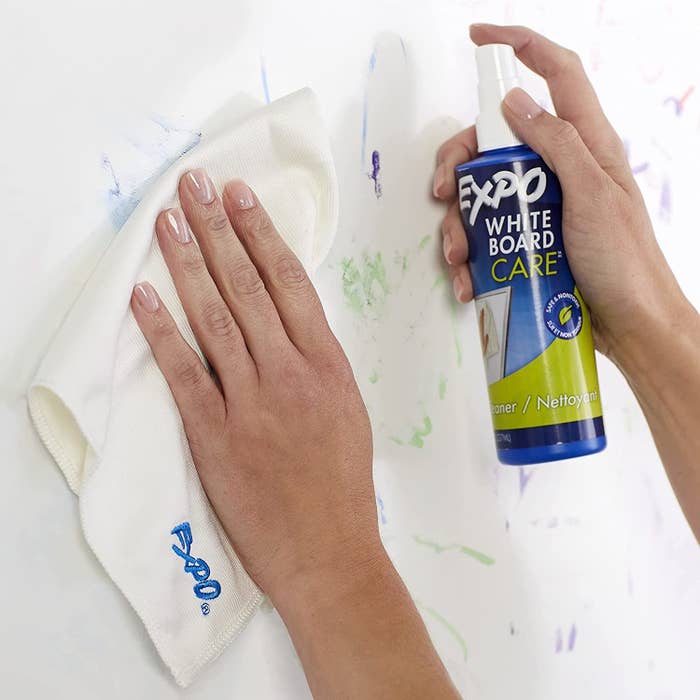 someone cleaning a whiteboard using the cleaning spray