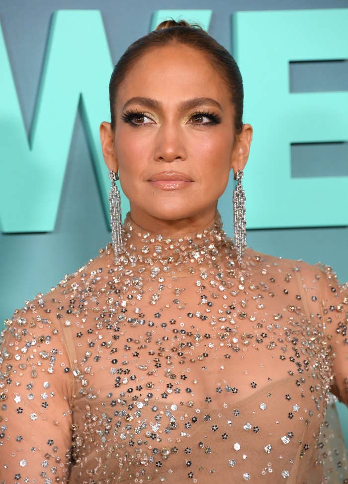 A close-up of Jennifer on the red carpet wearing a sheer dress with sequins. Her hair is pulled into a high bun