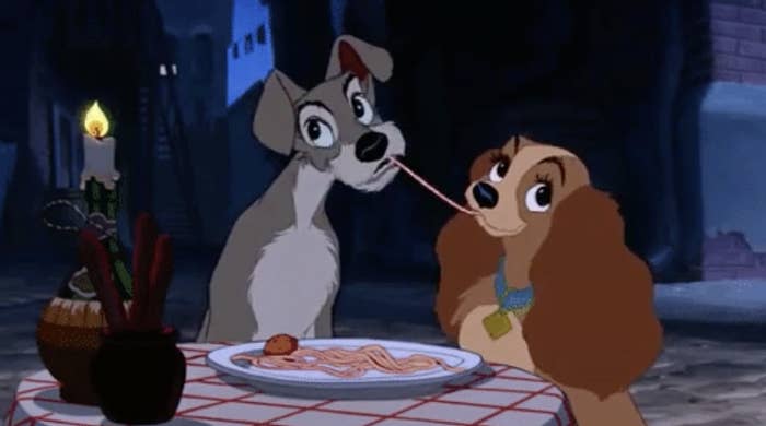 two dogs eating spaghetti at a dinner table
