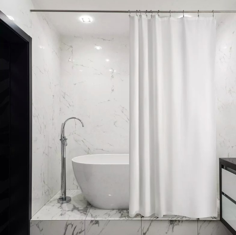 Shower curtain liner hanging in front of a freestanding tub