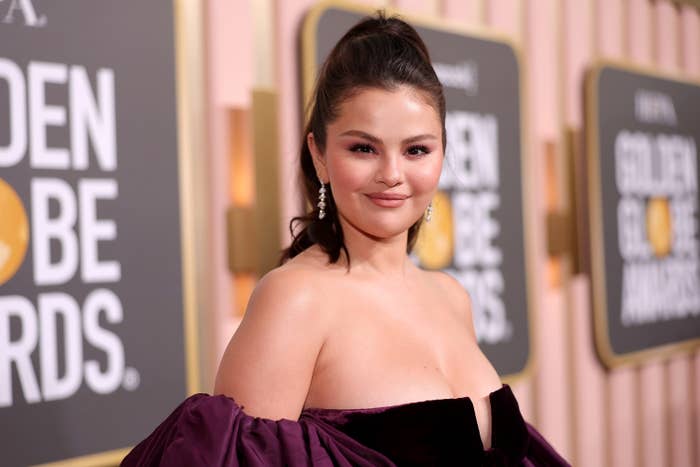 Selena smiles on the Golden Globes red carpet wearing a velvet strapless dress with balloon sleeves that start halfway down her arms