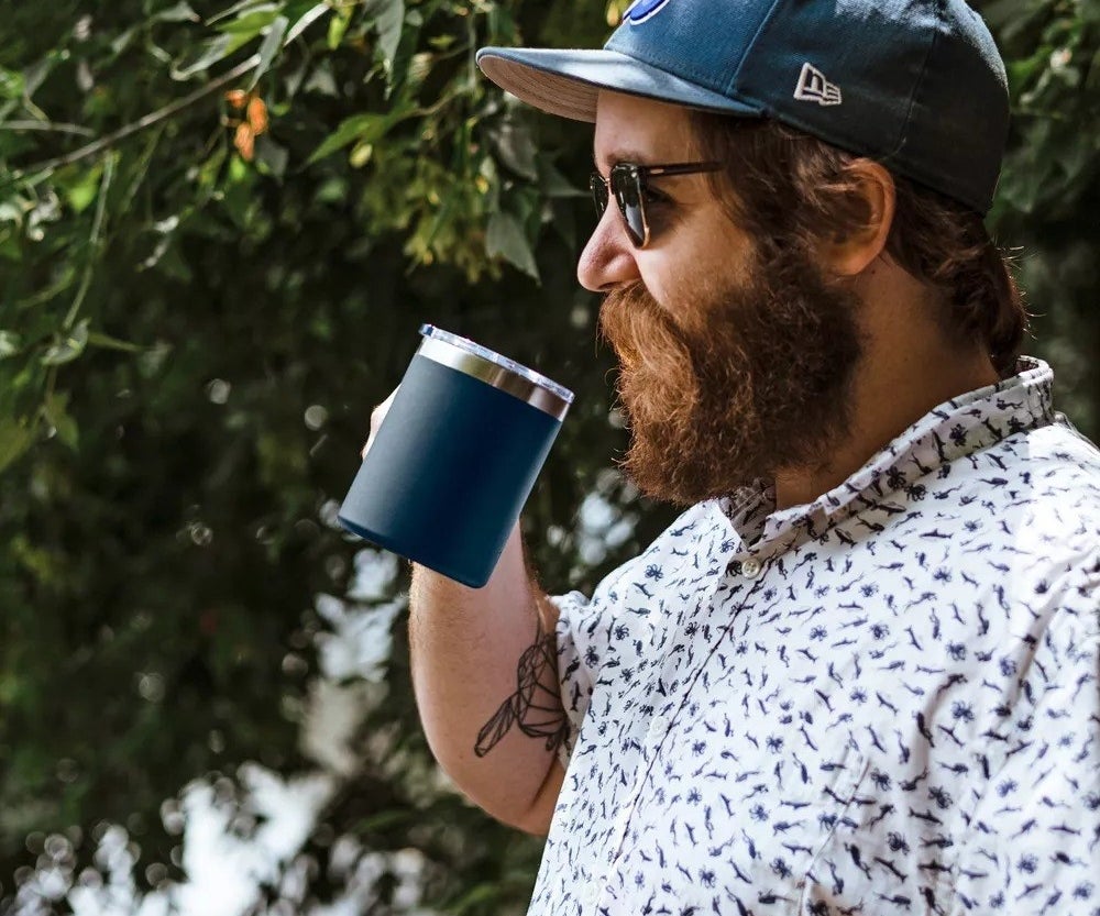 A model standing outside drinking from the blue insulated mug