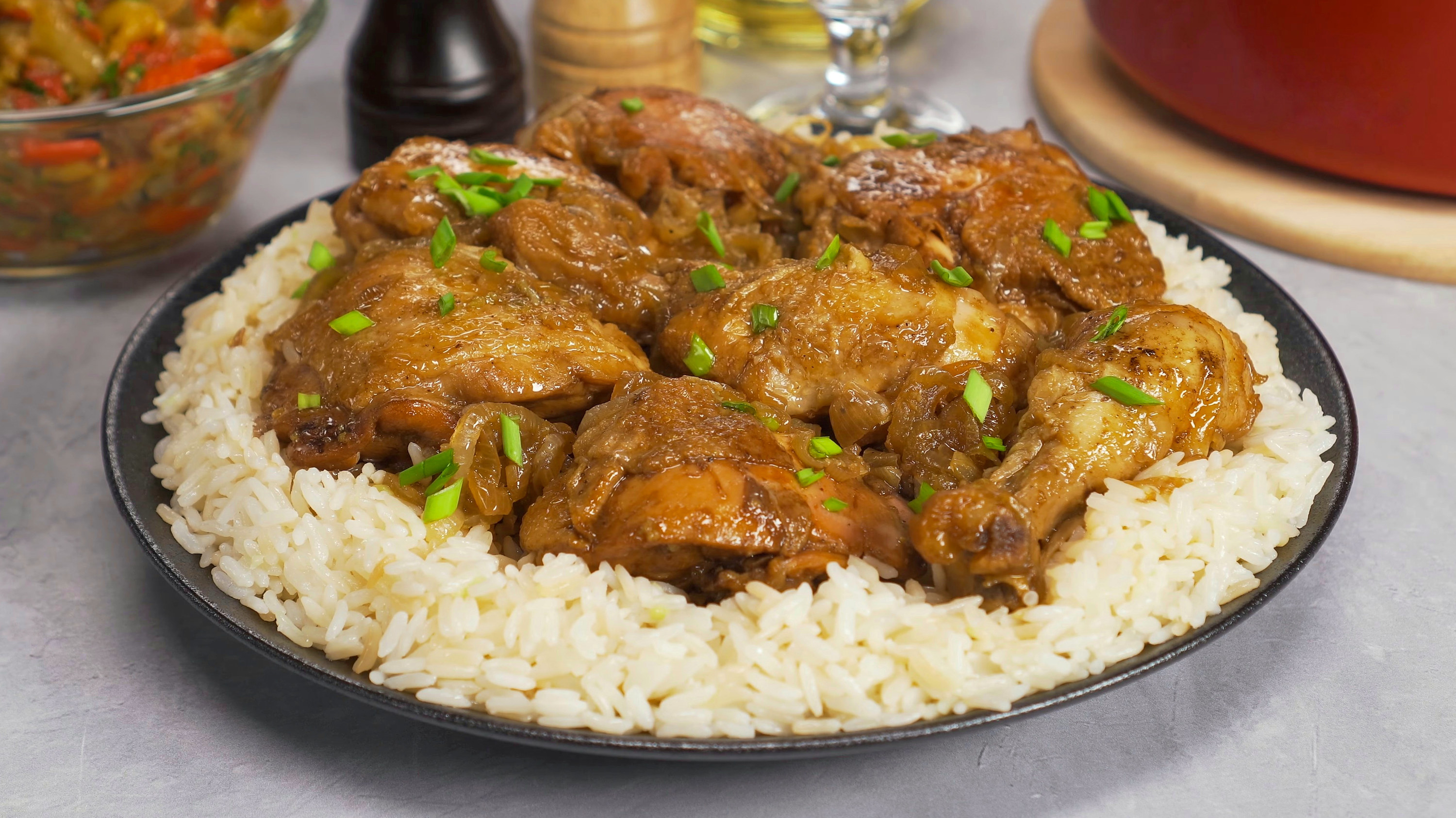A plate of Filipino chicken adobo which sits on a bed of white rice