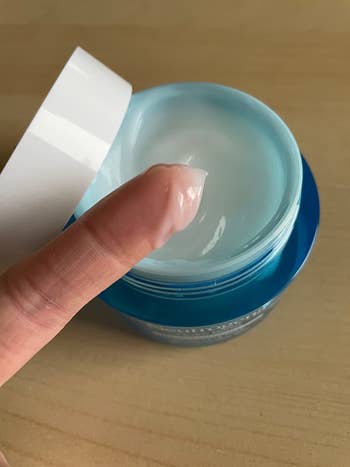 reviewer with some of the moisturizer on their finger to show the light creamy texture