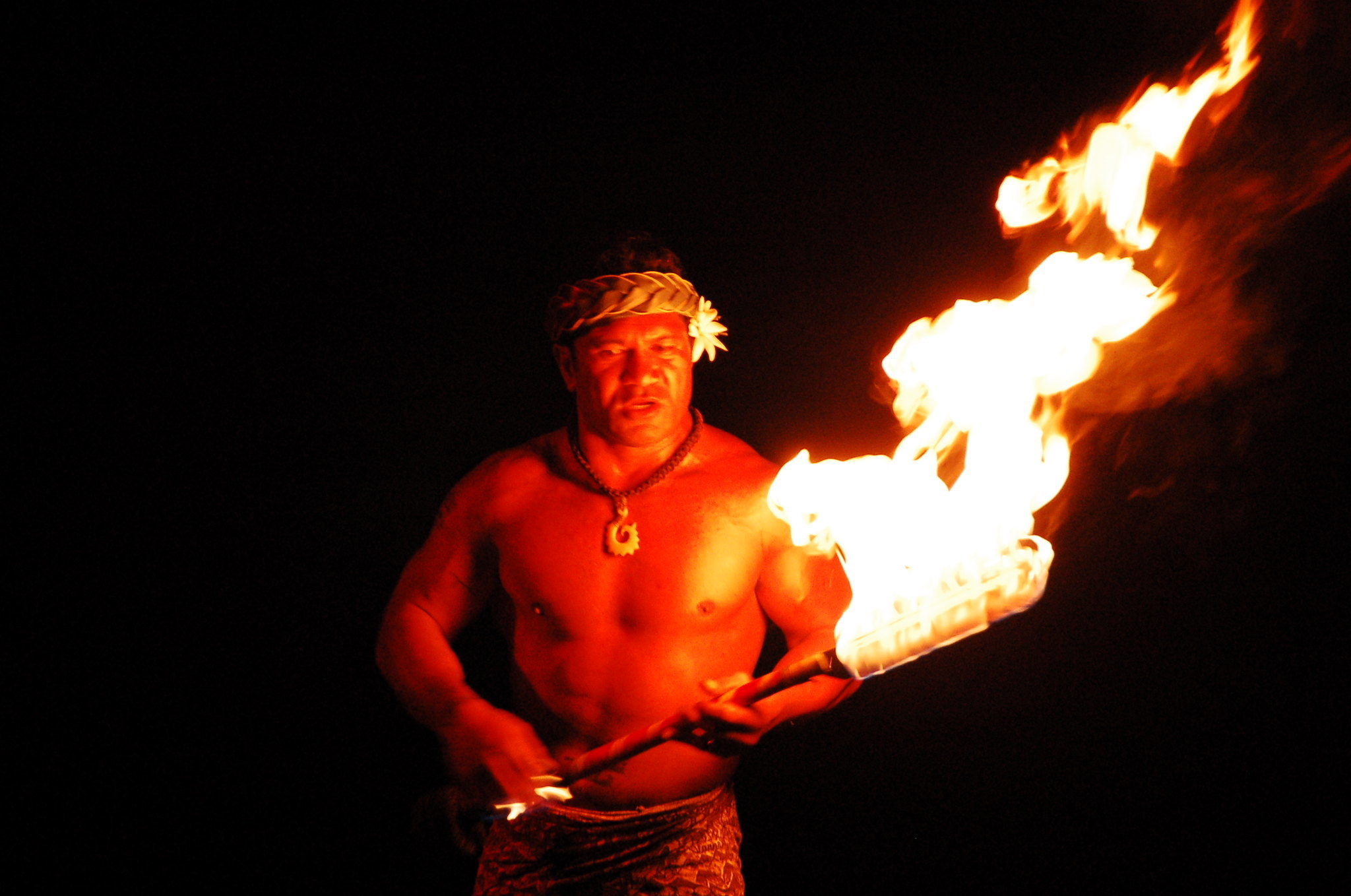 A man holding a flaming baton performs a siva.