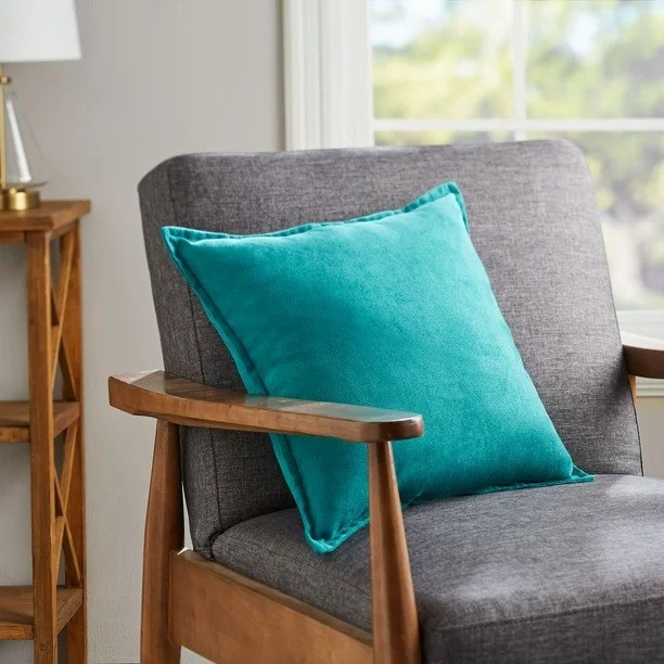 Teal decorative pillow resting on an accent chair