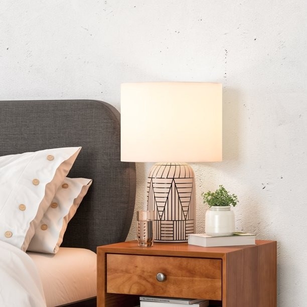A table lamp on a wooden night next to a bed