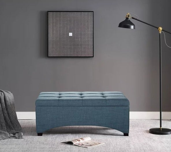 A blue storage ottoman on the floor in a bedroom