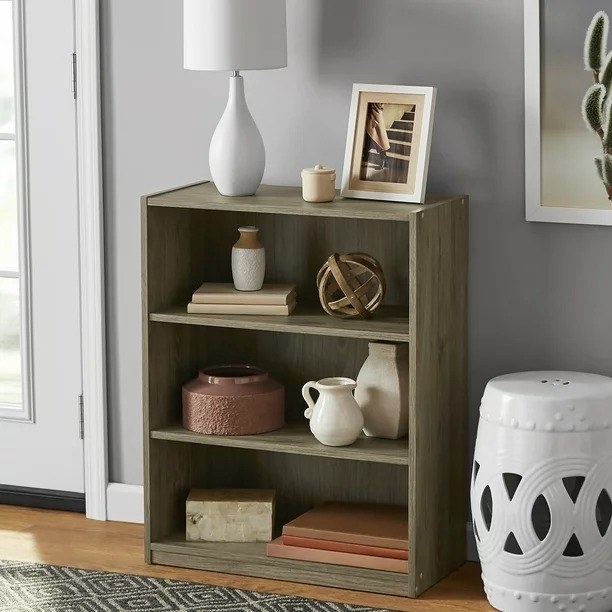 A rustic oak colored bookcase with bases and books on the shelves