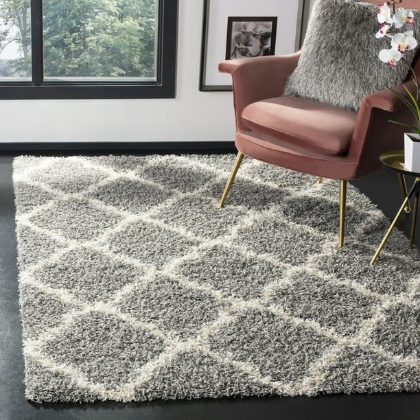 A patterned square area rug on the floor under an accent chair