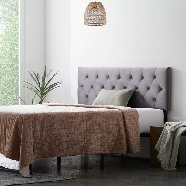 A gray headboard resting on a wall in a bedroom near a bed