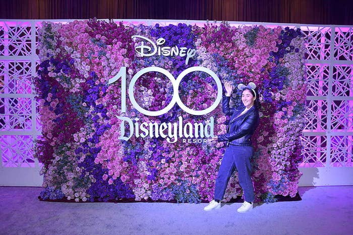 The author standing by a sign that says &quot;Disney 100 Disneyland Resort&quot;