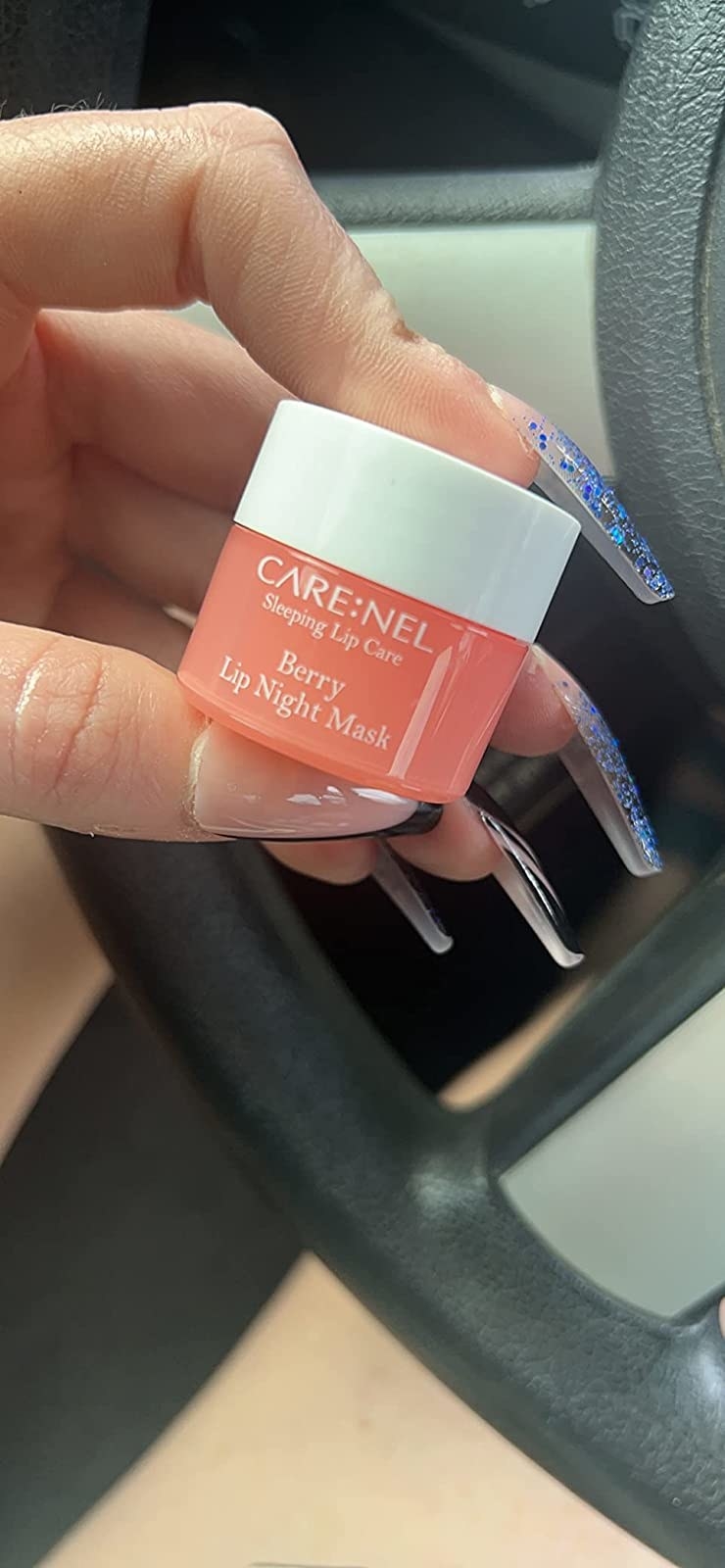 a reviewer holding the berry lip mask