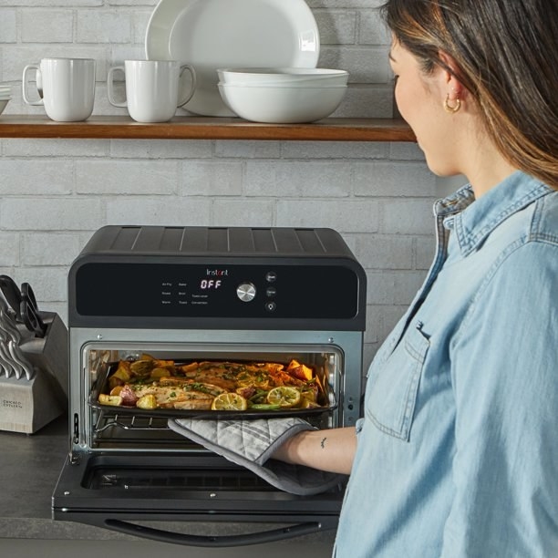 a person cooking french fries in an air fryer/toaster oven