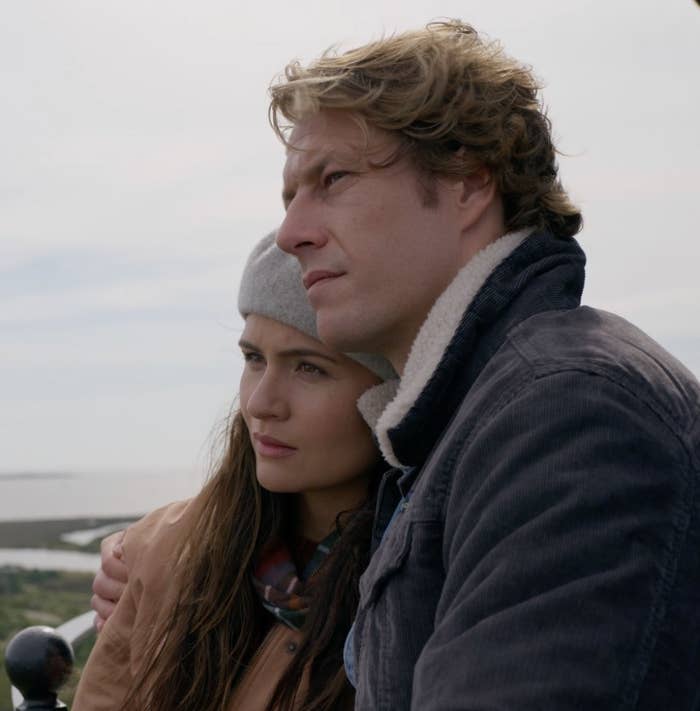 A woman and a man stand shoulder to shoulder, looking out into the distance.