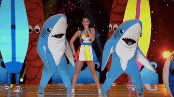 Katy Perry perfoms in between two people dressed as sharks