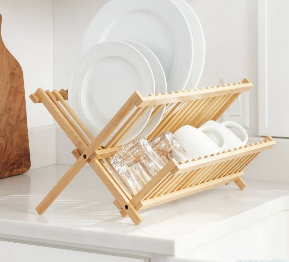 A bamboo drying rack holding white dishes and glasses