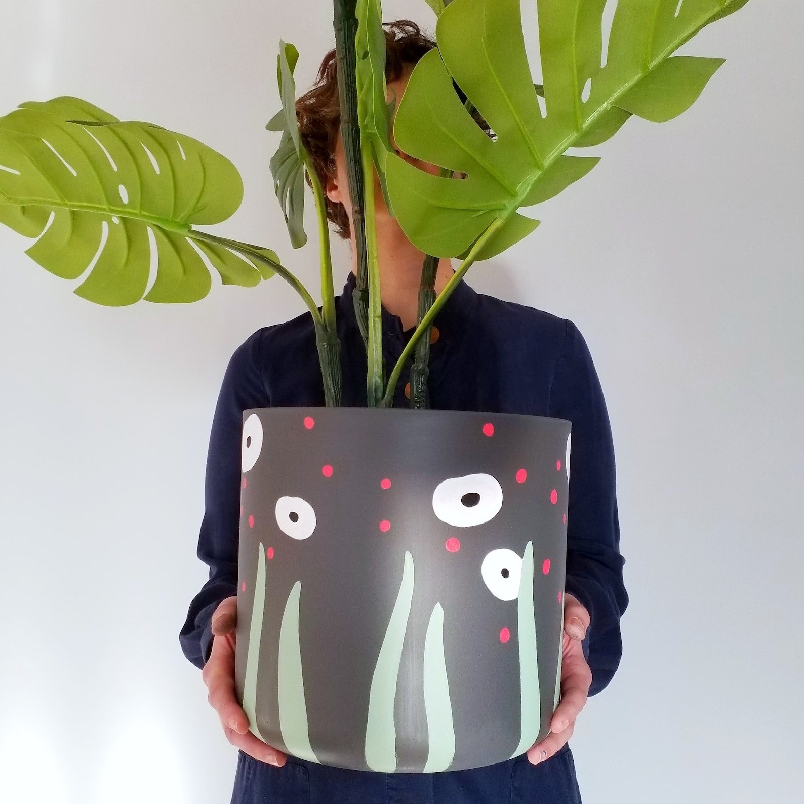 A person holds a planter with a colorful design painted on it