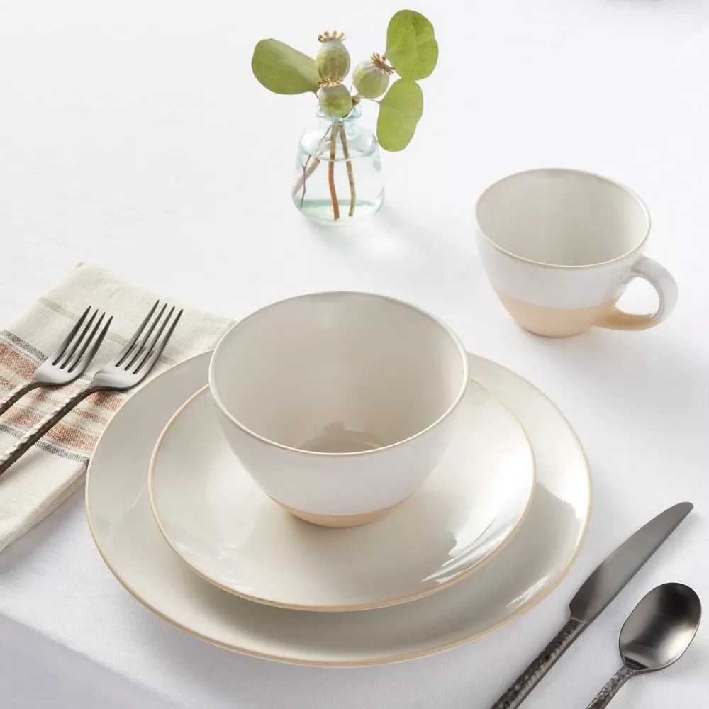 A place setting on a table with a dinner plate, salad plate, bowl, and mug