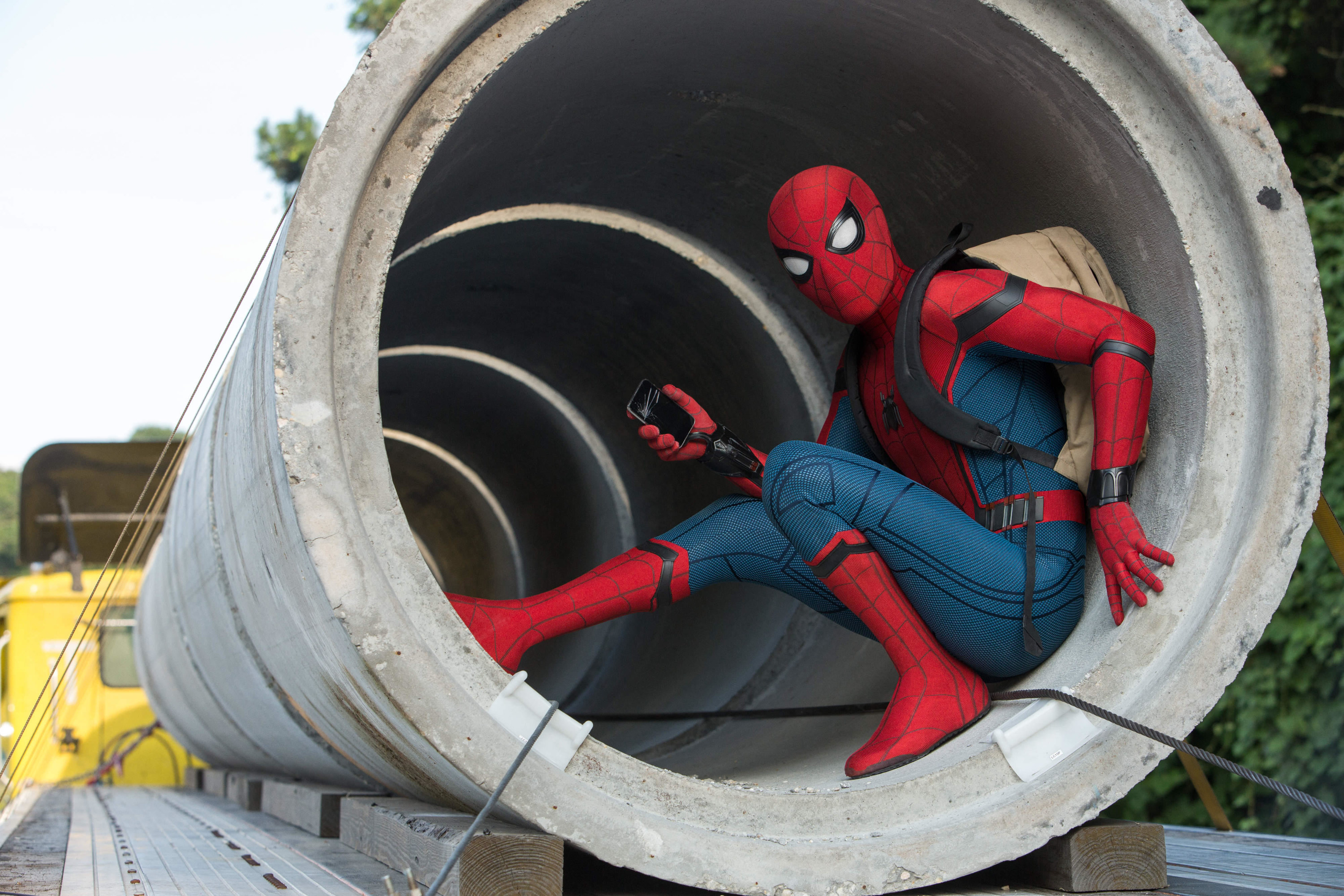 Spider-man lays low in a cement tube on a truck while wearing a backpack
