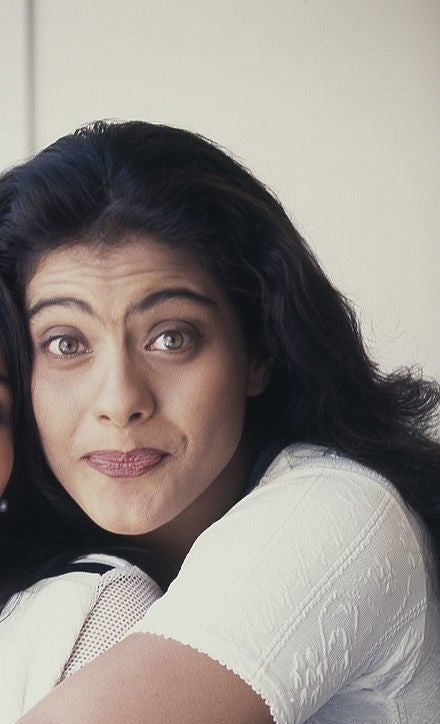 Kajol poses for a picture while hugging someone from behind