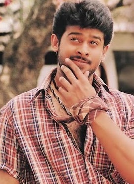 Prabhas smiles and touches his chin in a still from a film