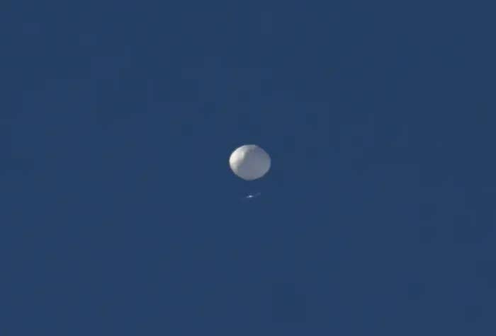 a single white balloon against a clear blue sky
