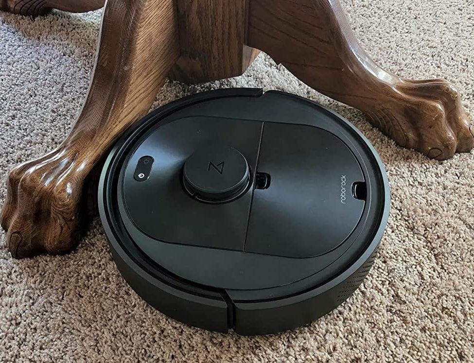 Reviewer's Roborock cleaning carpet next to table