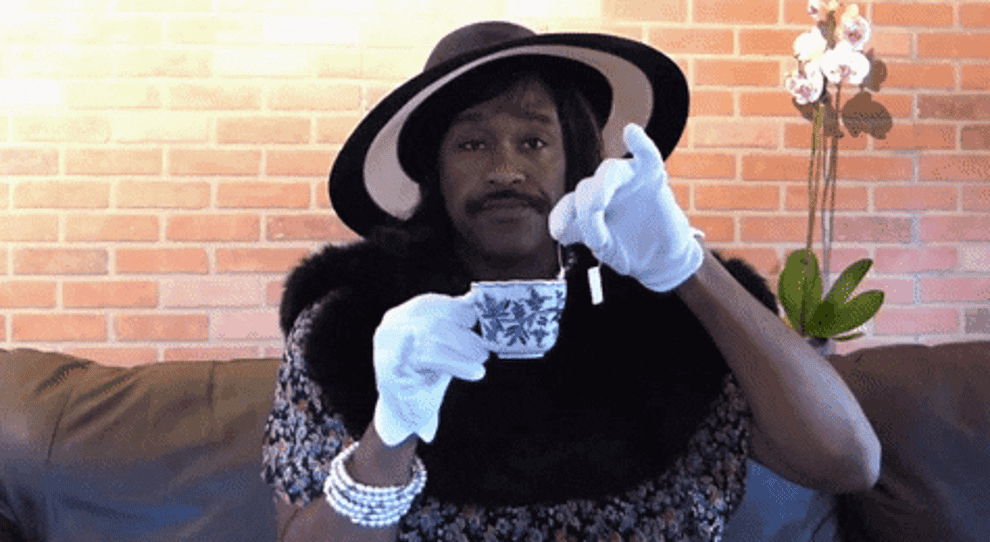 man stirring a tea dressed as a lady