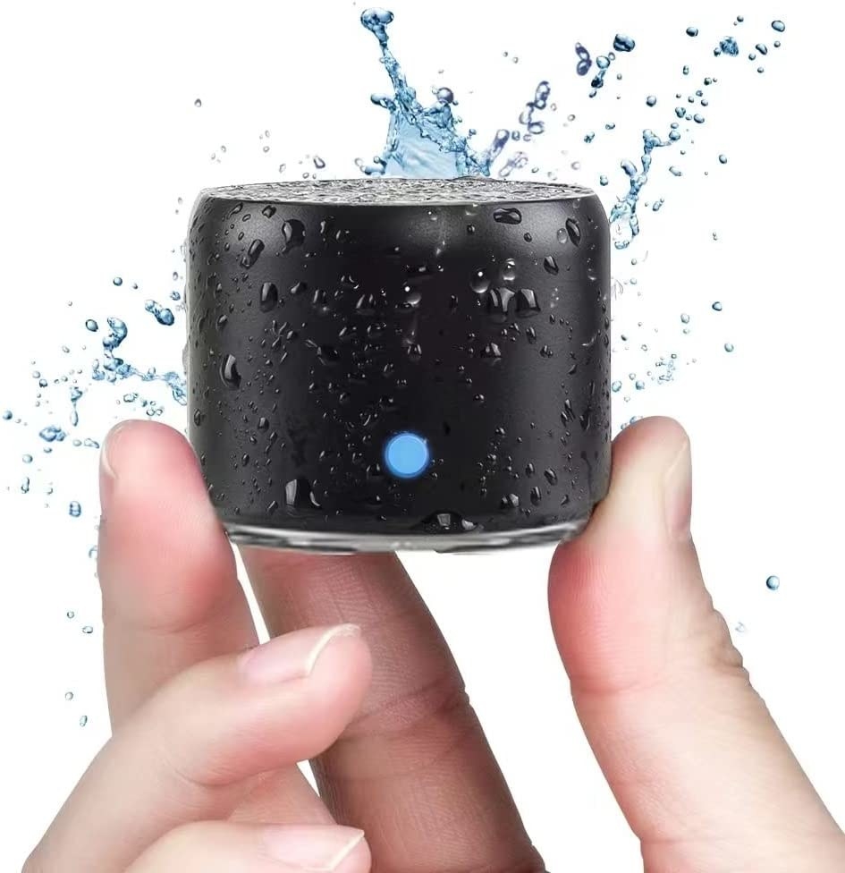 A model holding the small cylindrical speaker between their fingers with splashes of water