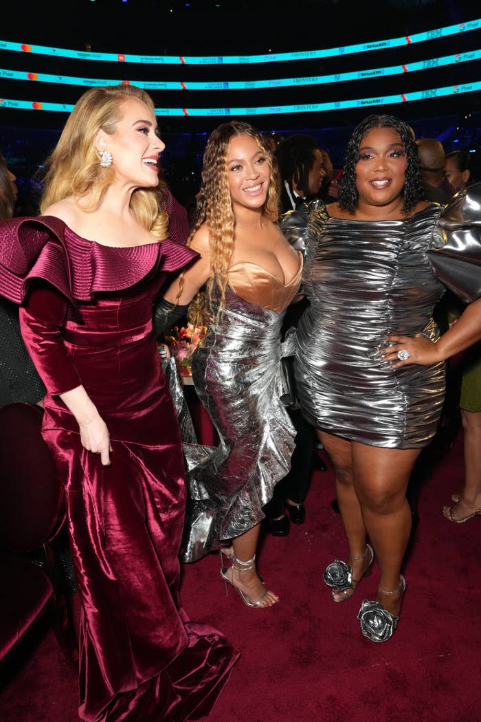 Adele and Lizzo smile as they pose for a picture with Beyoncé in the middle