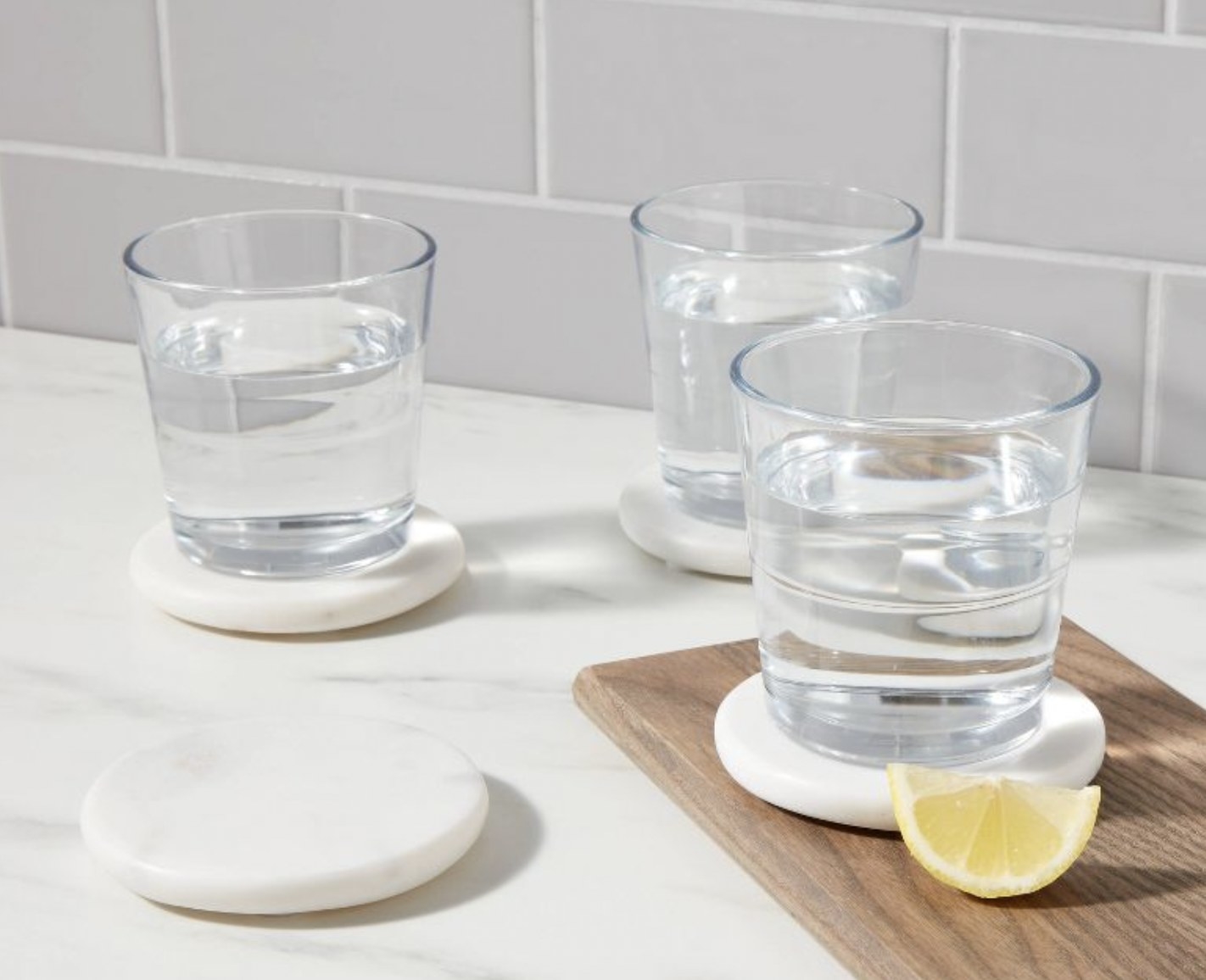 four white marble coasters with three glasses of water