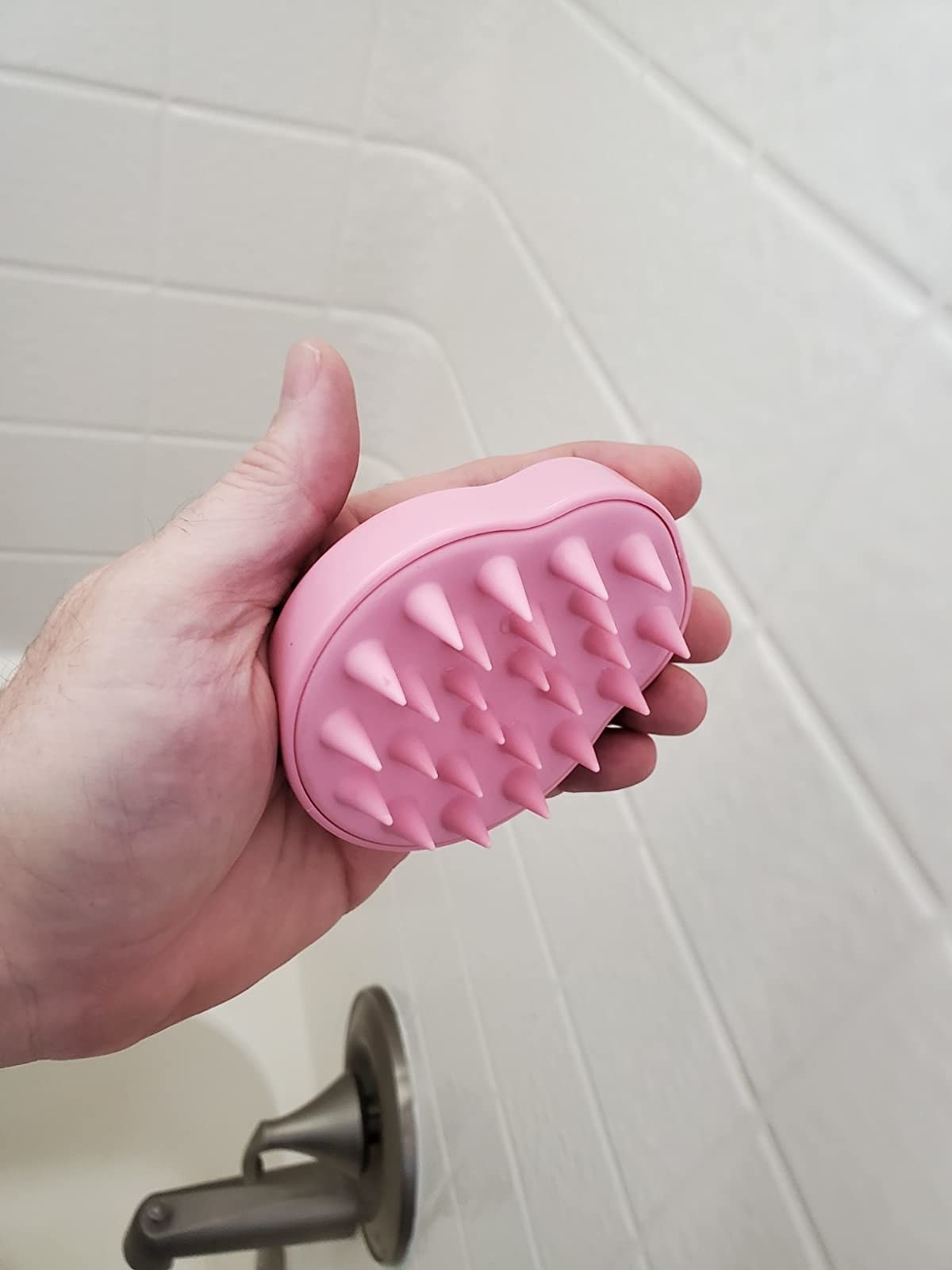 A reviewer holding the scalp massager in pink