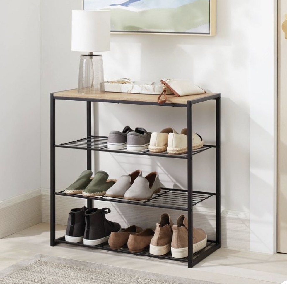 An entryway shoe rack with shoes on it and a lamp on the top tier