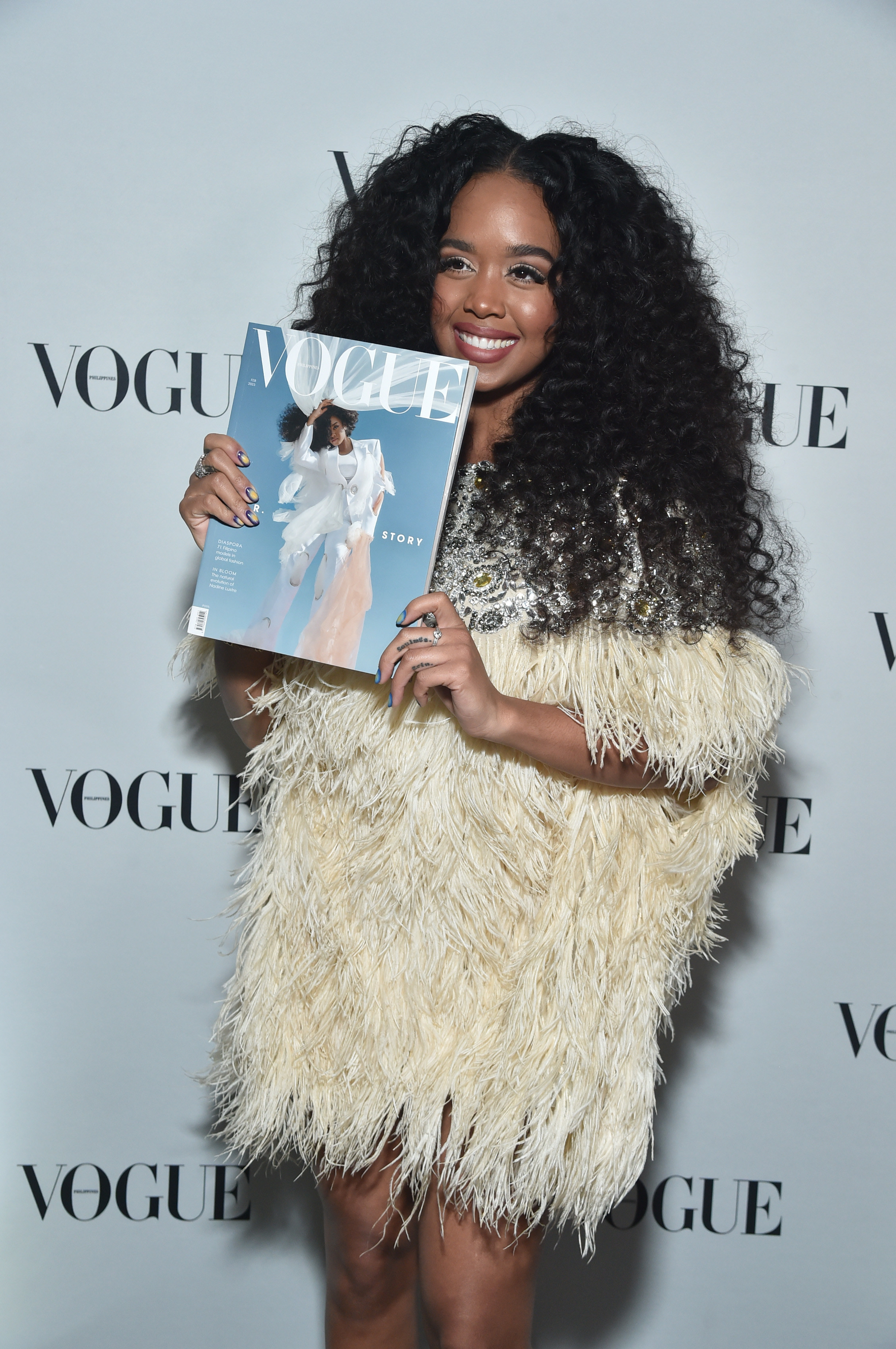 H.E.R. at the release party for her cover for Vogue Philippines holding up a copy of the magazine