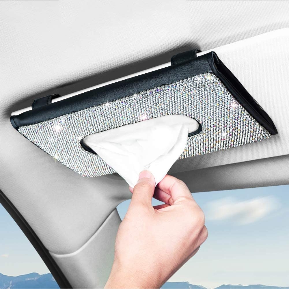 a person reaching for tissues from the holder in a car