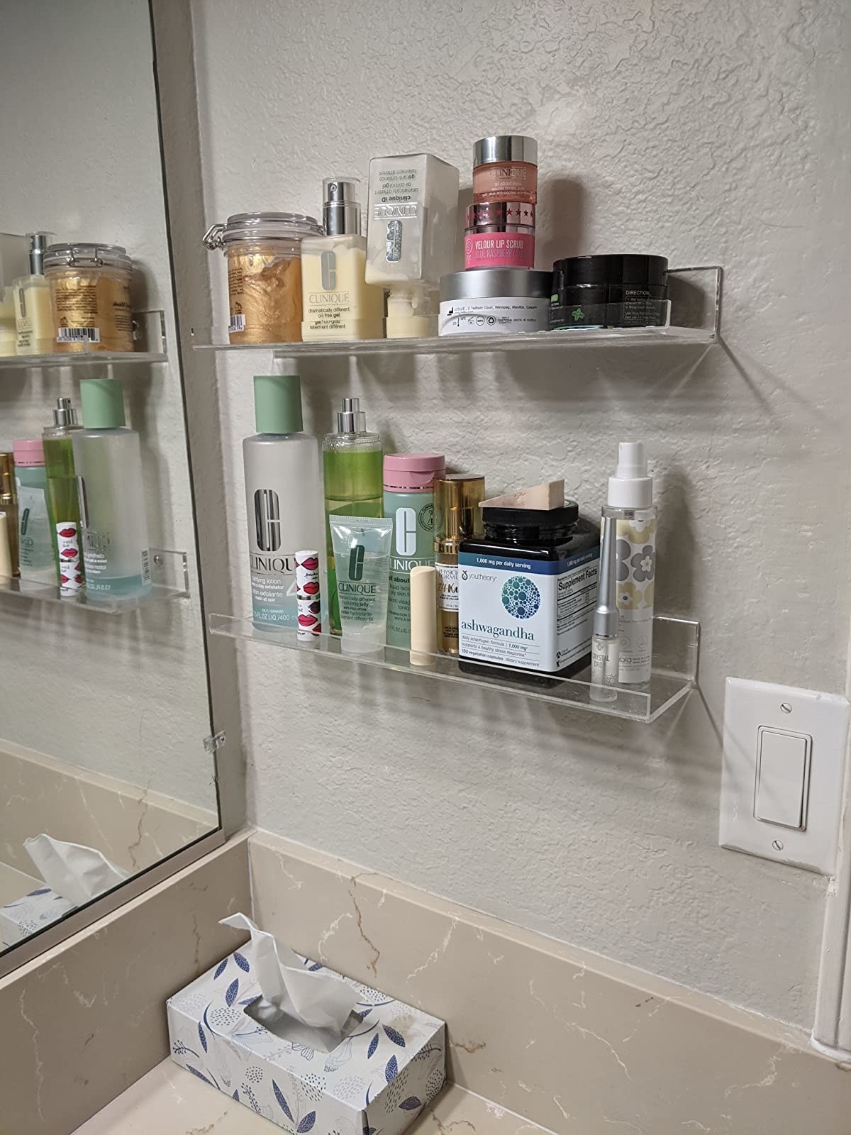 A reviewer&#x27;s shelves mounted in their bathroom with a lot of products on them