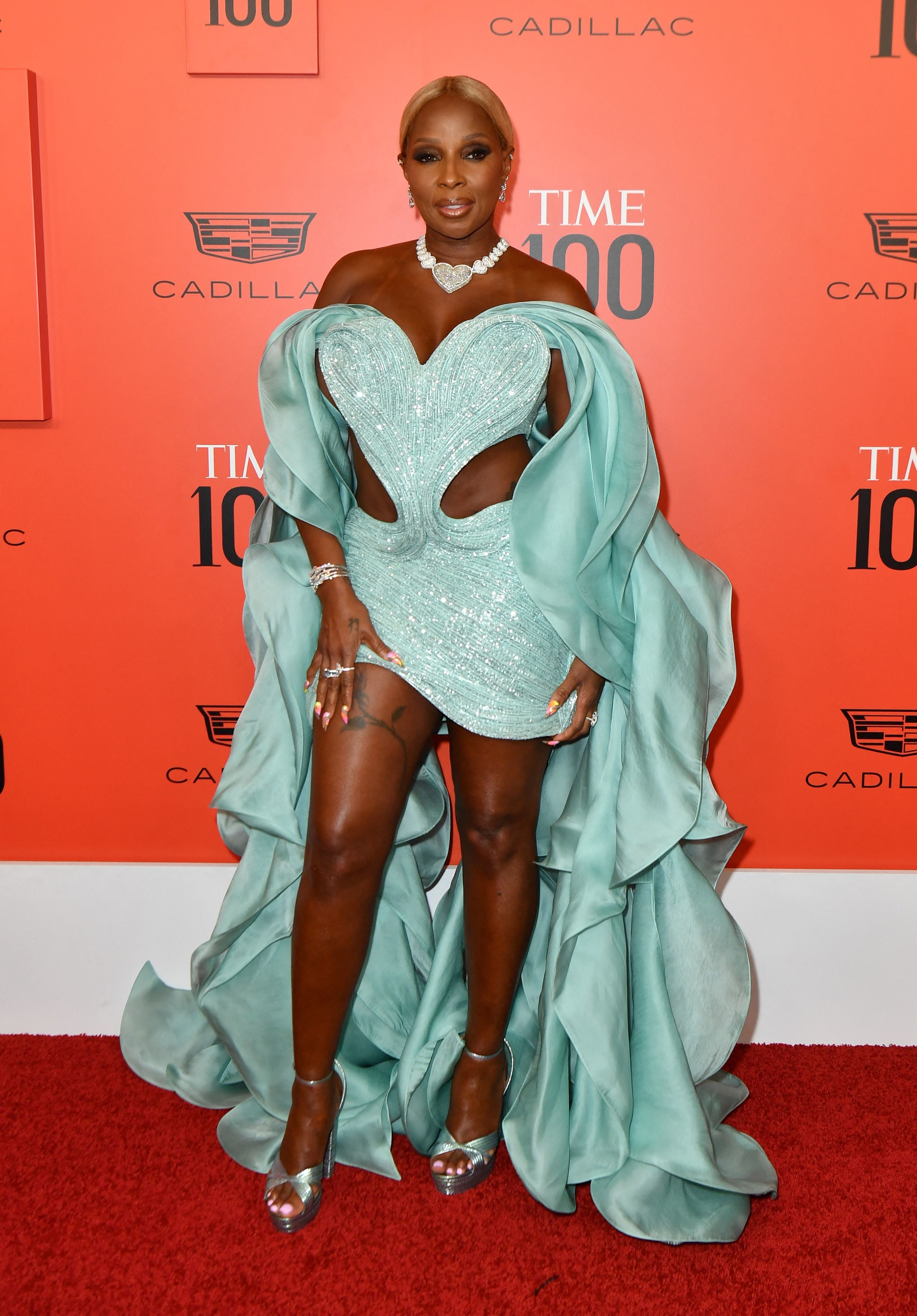 Mary J. Blige attends the 2022 Time 100 Gala in a short strapless gown that has sculptural sleeves that flow down her arms in waves