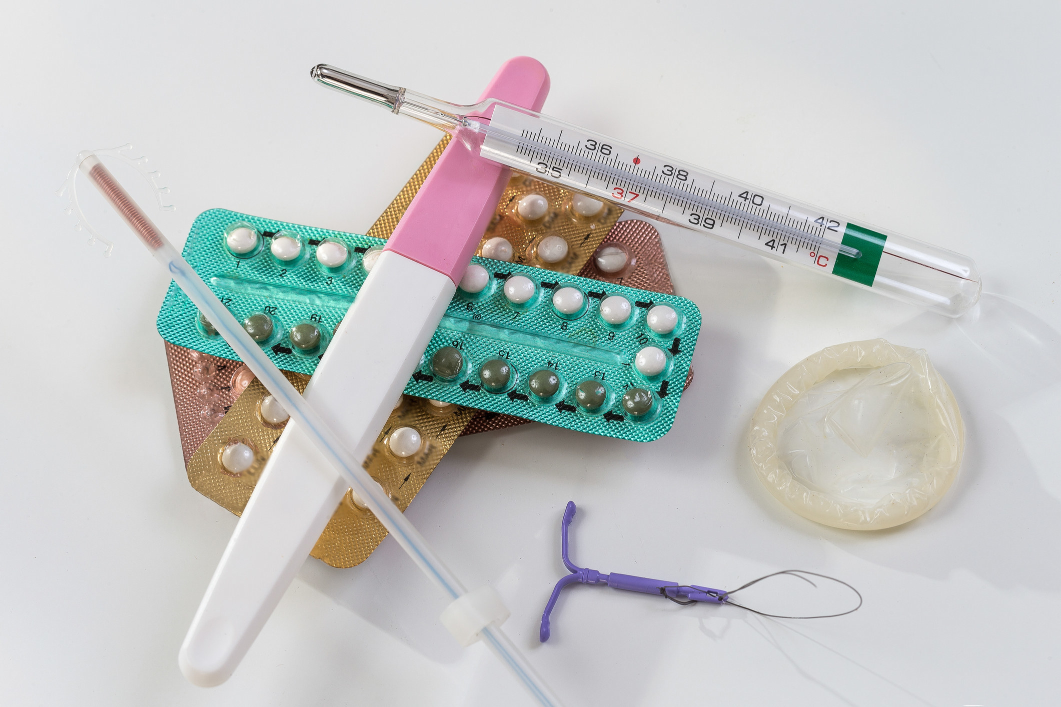 A stack of birth control options including an IUD, pills, and a vaginal ring